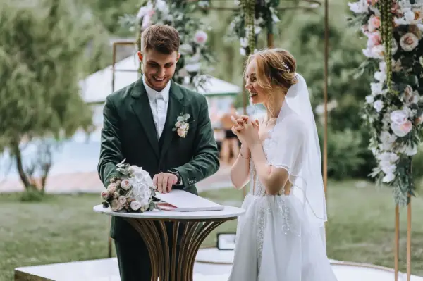 Para młoda podczas ceremonii ślubnej na tle dekoracji z kwiatów.
