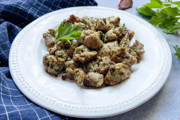 Deliciosas mollejas al ajillo, doradas y jugosas, servidas en un plato blanco con perejil fresco.