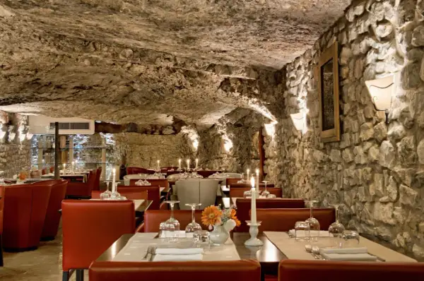Atmosfera suggestiva in una grotta, ideale per scoprire i migliori ristoranti a Vieste. Tavoli apparecchiati con candele e fiori.