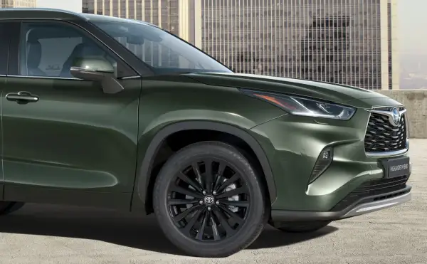 Elegancki, ciemnozielony Toyota Highlander 2025 z czarnymi felgami i nowoczesnym grillem, gotowy na miejskie wyzwania.