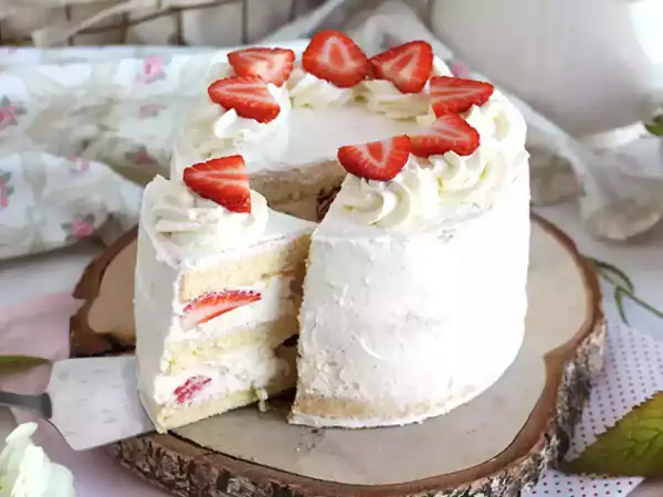 En vacker italiensk tårta med mascarpone, fylld med jordgubbar och täckt med fluffig grädde och färska jordgubbsbitar.