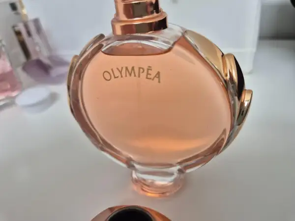 Olympea Paco Rabanne 80ml, w różowym odcieniu, otoczona złotymi zdobieniami.