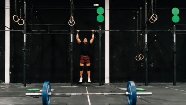Mężczyzna wykonujący podciąganie na drążku w siłowni CrossFit.