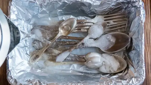 Srebrne sztućce w folii aluminiowej, zalewane wrzątkiem z solą. Prosty sposób, jak wyczyścić srebro w domu.