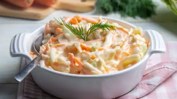Deliciosa ensalada americana cremosa, con repollo y zanahoria rallados, adornada con eneldo fresco.