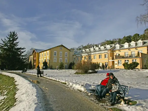 Zimowy krajobraz przed żółtym sanatorium. Zastanawiasz się, ile kosztuje turnus w sanatorium?