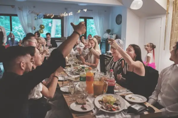 Radosne chrzciny w domu. Rodzina wznosi toasty przy suto zastawionym stole, świętując ważne wydarzenie.