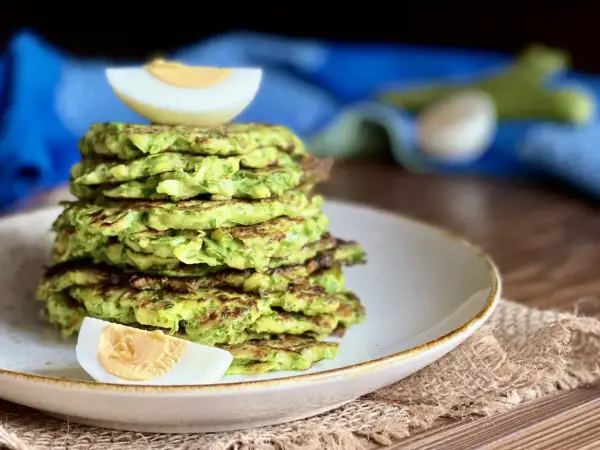 Pila di rosti di zucchine dorati, guarnita con spicchi di uovo sodo. Un piatto leggero e gustoso.