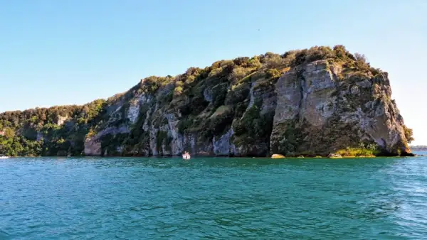 Un'emozionante visita all'isola Martana, con le sue scogliere imponenti e il mare turchese. Una piccola barca si avvicina alla costa rocciosa.