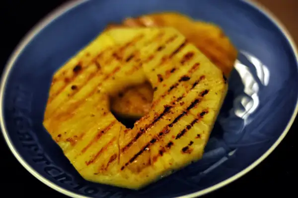 Tranches d'ananas grillées sur une assiette bleue.