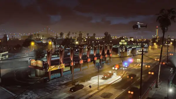 Nocne miasto w GTA 5, policyjne syreny, helikopter i neonowy szyld "Car Wash".
