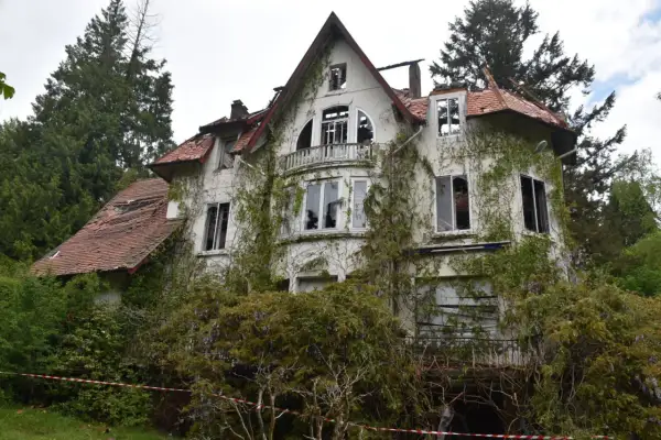 Maison abandonnée envahie par la végétation, parfaite pour faire de l'urbex. Toit endommagé, fenêtres brisées, un lieu chargé d'histoire.