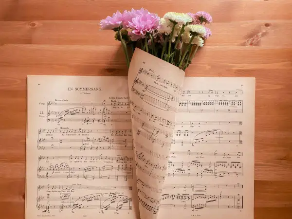 Un mazzo di fiori rosa e bianchi adagiato su spartiti musicali. Le note sembrano le canzoni della mamma, piene di dolcezza.