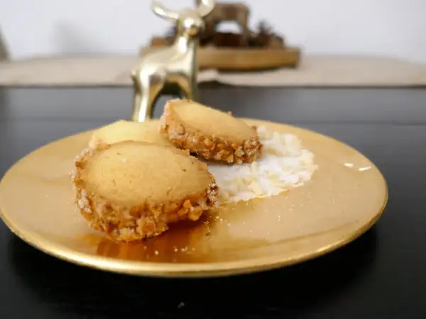 Goldene Platte mit drei Friesenkeksen, bestreut mit Zucker und gehackten Mandeln. Ein goldener Hirsch im Hintergrund. Das ist das original Friesenplätzchen Rezept.