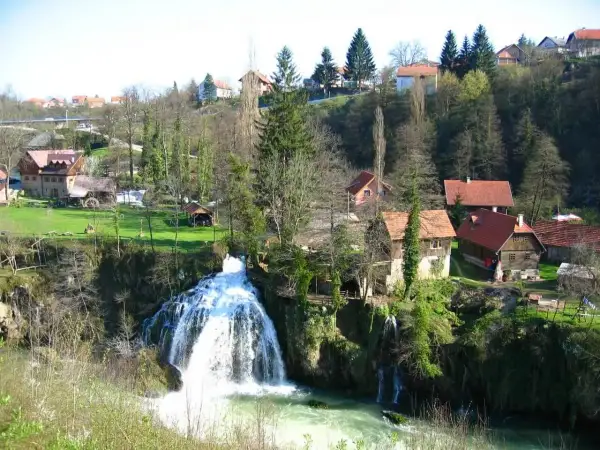 Magnifique cascade en Croatie, avec des maisons traditionnelles nichées dans la verdure. Un paysage pittoresque.