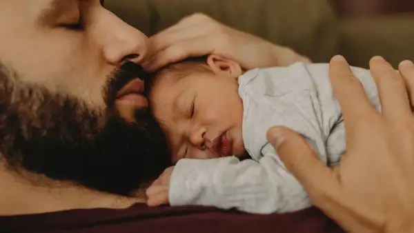 En pappa tröstar sin bebis som gråter hela tiden. Bebisen sover lugnt mot pappans bröst.