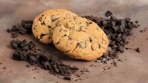 Due golosi crumble cookies con gocce di cioccolato, circondati da pezzetti di cioccolato fondente. La ricetta perfetta per un momento di dolcezza.