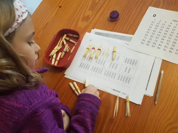 Niña concentrada con pajitas y gomas para resolver operaciones matemáticas, aplicando el método ABN infantil.
