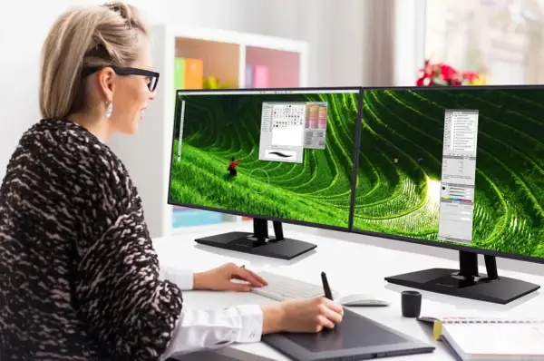 Kobieta pracuje przy dwóch monitorach z wąską ramką (bezel), edytując zdjęcie tarasów ryżowych.