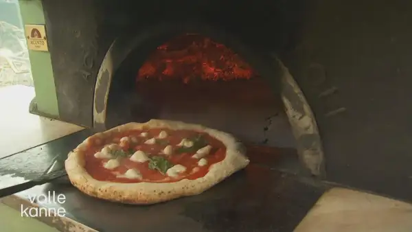 Eine authentische Pizza Napoletana mit Mozzarella und Basilikum wird in einem Holzofen gebacken.