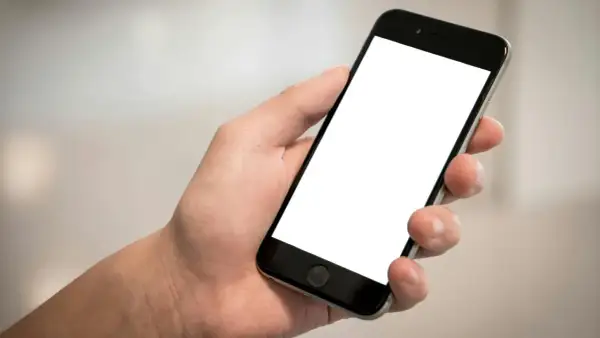 Dłoń trzyma smartfon z pustym ekranem. Chcesz wiedzieć, jak sprawdzić telefon?
