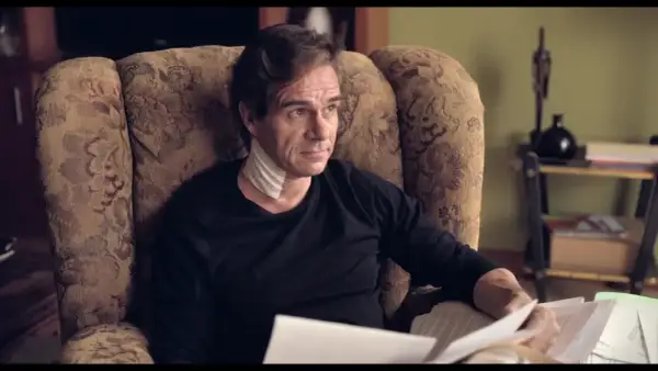Uomo con benda al collo, seduto su una poltrona, legge documenti. L'altezza di Tony Boy è un mistero.