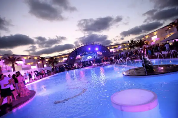 Festa in piscina a Ibiza con DJ set e folla festante. Un'atmosfera vibrante per gli eventi di Ibiza a settembre.
