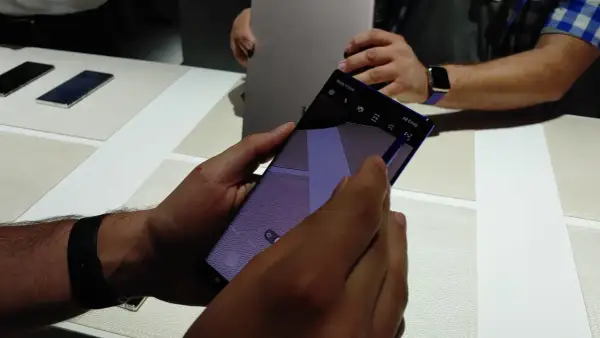 Ręka trzyma smartfon z włączoną funkcją AR Emoji. Widać ikonę "AR Emoji" na ekranie.
