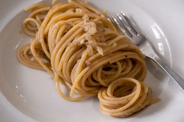 Un piatto di bigoli con le sarde, pasta fresca condita con un sugo saporito.