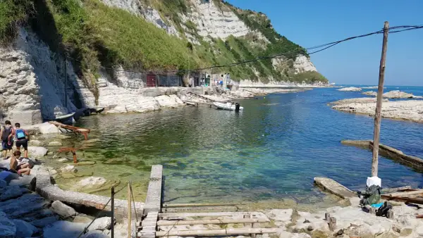 La spiaggia della Scalaccia, con le sue acque cristalline e le scogliere bianche, accoglie bagnanti e piccole imbarcazioni.