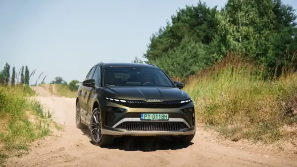 Zielona Skoda Enyaq na piaszczystej drodze, testowana pod kątem zasięgu.