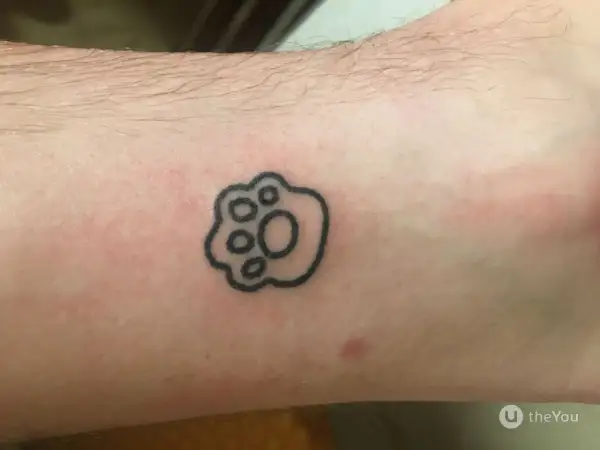 Małe tatuaże męskie: czarna łapka zwierzęcia na skórze, symbol przyjaźni i lojalności.