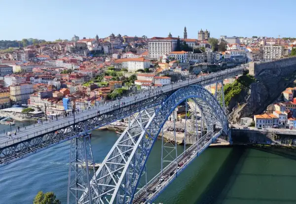 Most Louisa Martinez wino, widok na most Ponte de Dom Luís I w Porto, Portugalia, z zabytkową zabudową w tle.