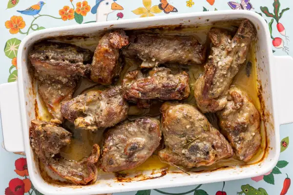 Pezzi succulenti di abbacchio alla romana cotti in teglia, dorati e profumati, pronti per essere gustati.