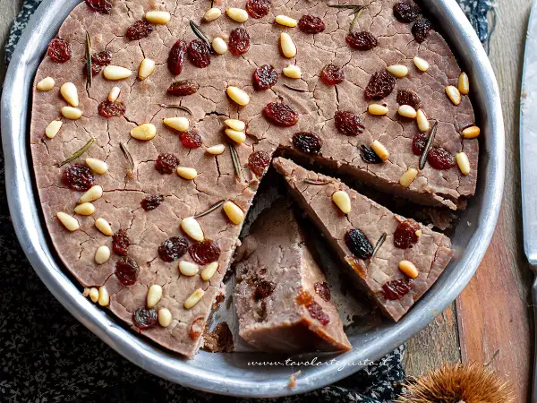 Delizioso castagnaccio con latte, guarnito con pinoli, uvetta e rosmarino. Una ricetta tradizionale per un dolce autunnale.