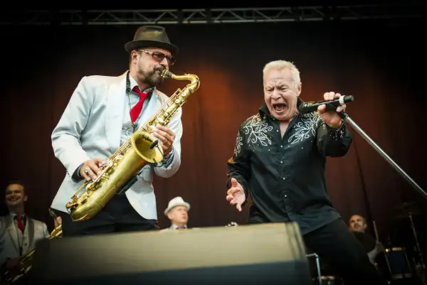 Stellan Sundahl sjunger med full kraft medan en saxofonist ackompanjerar.