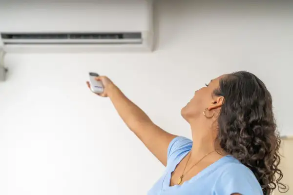 Donna con telecomando regola il condizionatore dal design elegante. La canalina è quasi invisibile, integrata perfettamente.