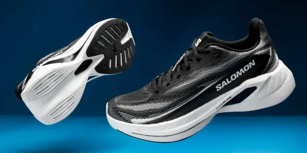Deux chaussures de course Salomon Spectur noires et blanches, avec semelles blanches et noires, sur fond bleu.