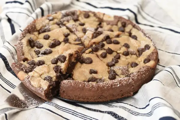 En kladdkaka med cookie dough och chokladbitar, pudrad med florsocker. En bit är uppskuren.