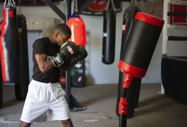 A boxer practices boxing drills in a gym, surrounded by various punching bags.
