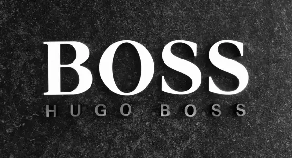 Białe litery "BOSS" na ciemnym, kamiennym tle. Poniżej mniejsze litery "HUGO BOSS". To symbol marki z bogatą historią.