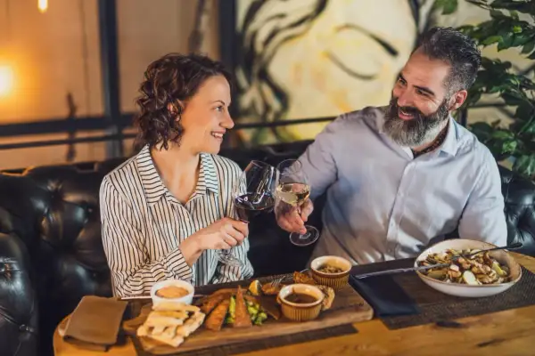 Para celebruje w najdroższej restauracji w Warszawie. Wznoszą toast winem, delektując się wykwintnym jedzeniem.