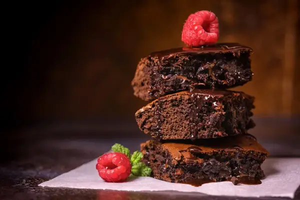 Stos pysznych, wilgotnych brownie z polewą czekoladową i malinami. Idealny brownie prosty przepis na domowe ciasto.