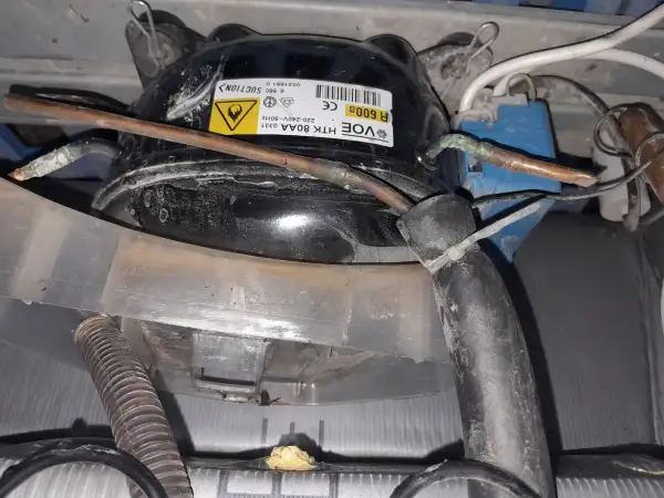 Lodówka Whirlpool nie chłodzi, ale zamrażarka działa. Widoczny kompresor z etykietą R600A.