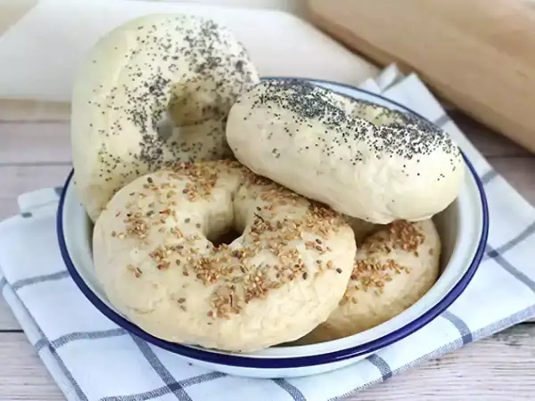 Färska bagels med vallmofrön och sesamfrön i en skål, redo för ett gott bagels recept.
