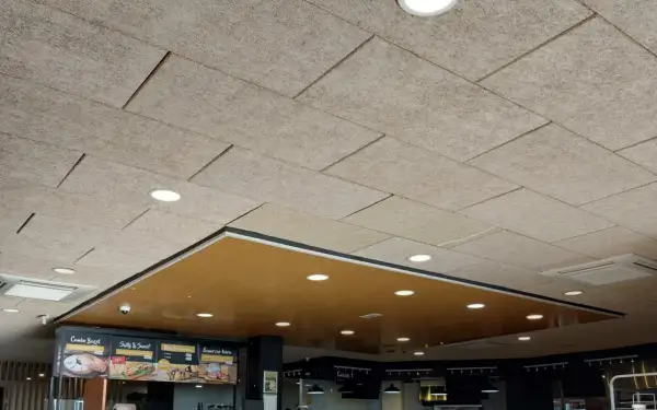 Techo celenit con paneles texturizados y luces empotradas, creando un ambiente moderno y acogedor.