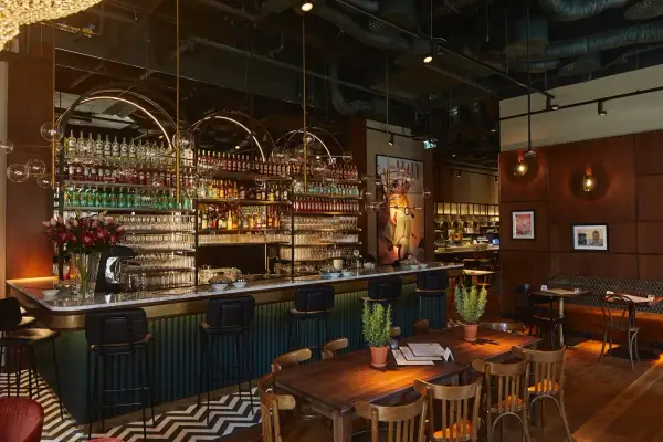 Elegancki bar z mnóstwem butelek alkoholu i kieliszków, idealne miejsce na odkrywanie ciekawych restauracji w Warszawie.