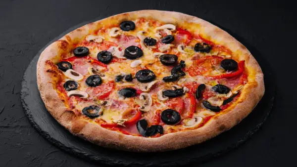 Chrupiąca pizza z oliwkami, pieczarkami i papryką na czarnym tle.