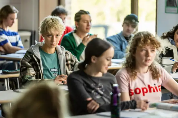 Młodzi ludzie na lekcji, zastanawiają się, fanfik co to. Jedna z dziewczyn ma blond włosy i patrzy wprost.