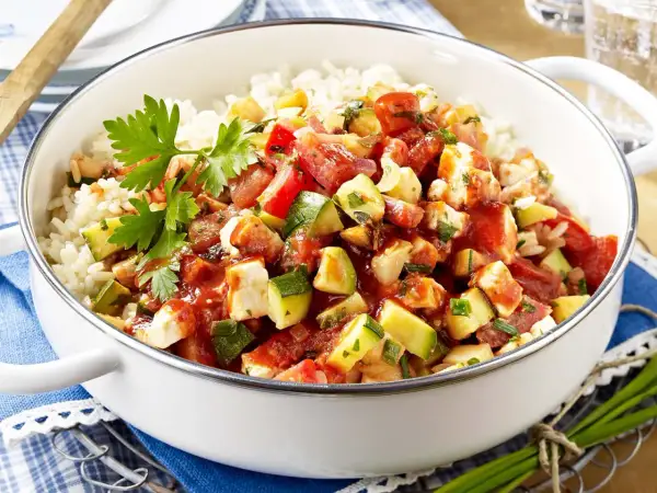 Eine köstliche zucchini-reis-pfanne einfach zubereitet mit viel Gemüse und Hähnchen. Frisch garniert mit Petersilie.